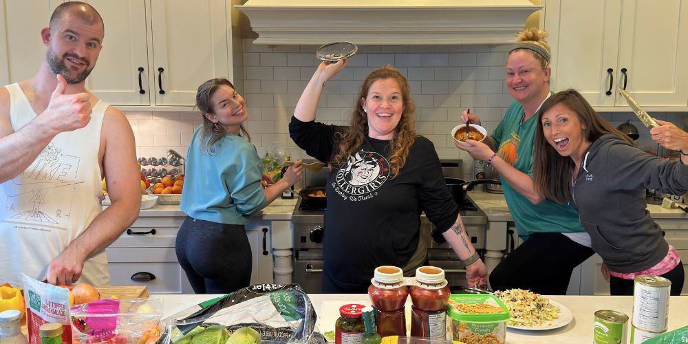 Joymaker participants smiling and preparing a meal together in the kitchen