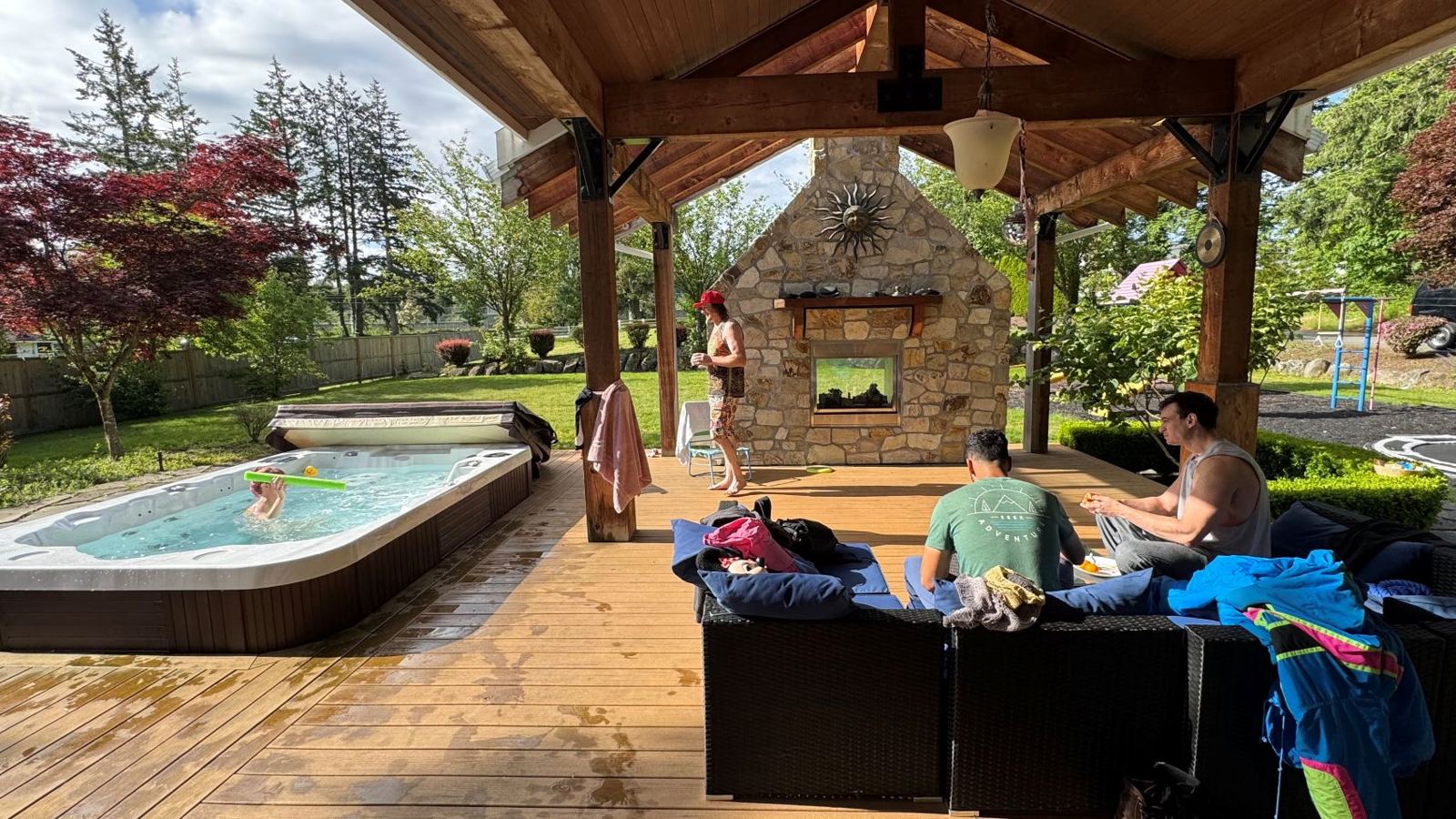 The covered outdoor pavilion with seating, a fireplace, and hot tub